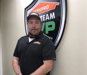 A man standing in front of a green SERVPRO sign
