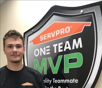 A man standing in front of SERVRPO one team sign