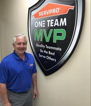 Male smiling and standing in front of SERVPRO sign