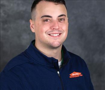 SERVPRO employee in front of blue wall smiling