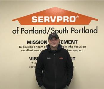 A man wearing a hat standing in front of SERVPRO wall