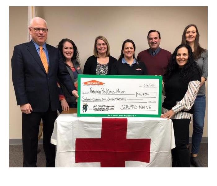 7 people standing holding a check for $16,700 for the American Red Cross