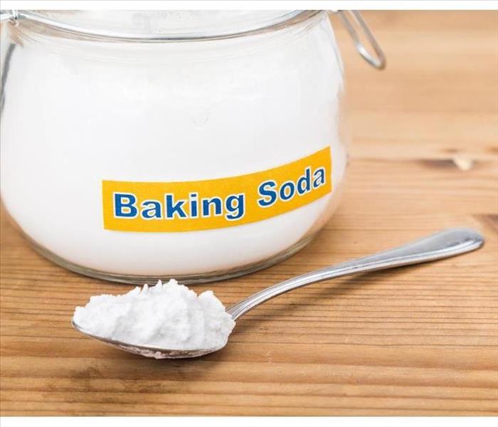 spoonful of baking soda and a jar on a wooden table